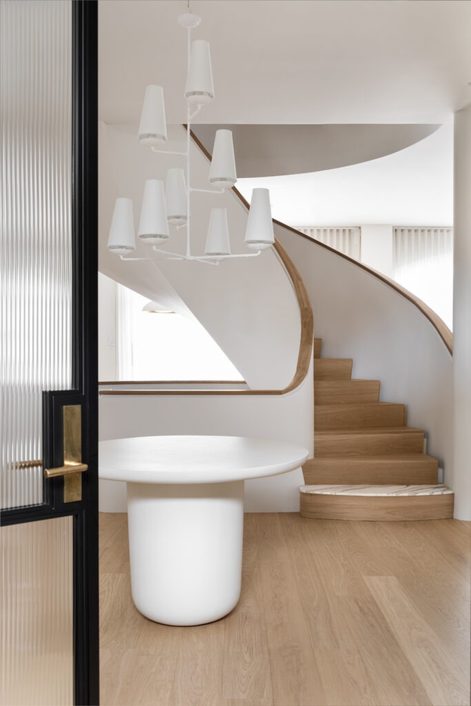 Curved plaster staircase with white oak handrail. White oak with marble tread detail.